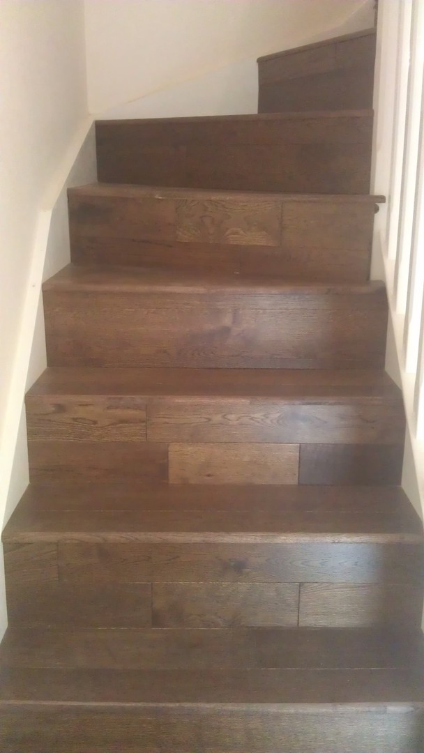 Staircase re-clad in dark engineered oak boards with mixed-width treads and risers by LMB Joinery.